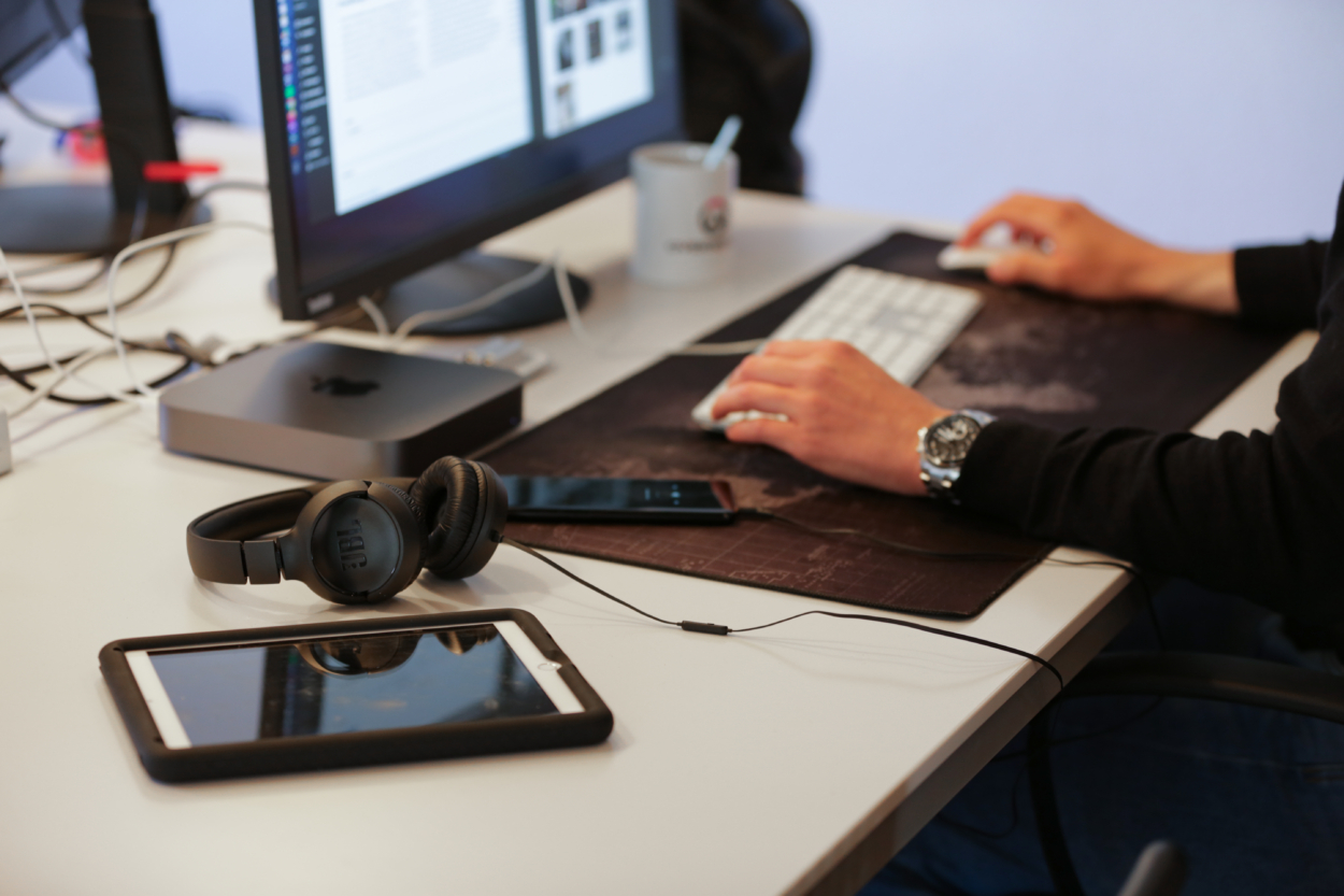 Der Bildaussschnitt zeigt Hände, die an einem Computer mit Tastatur und Maus arbeiten.