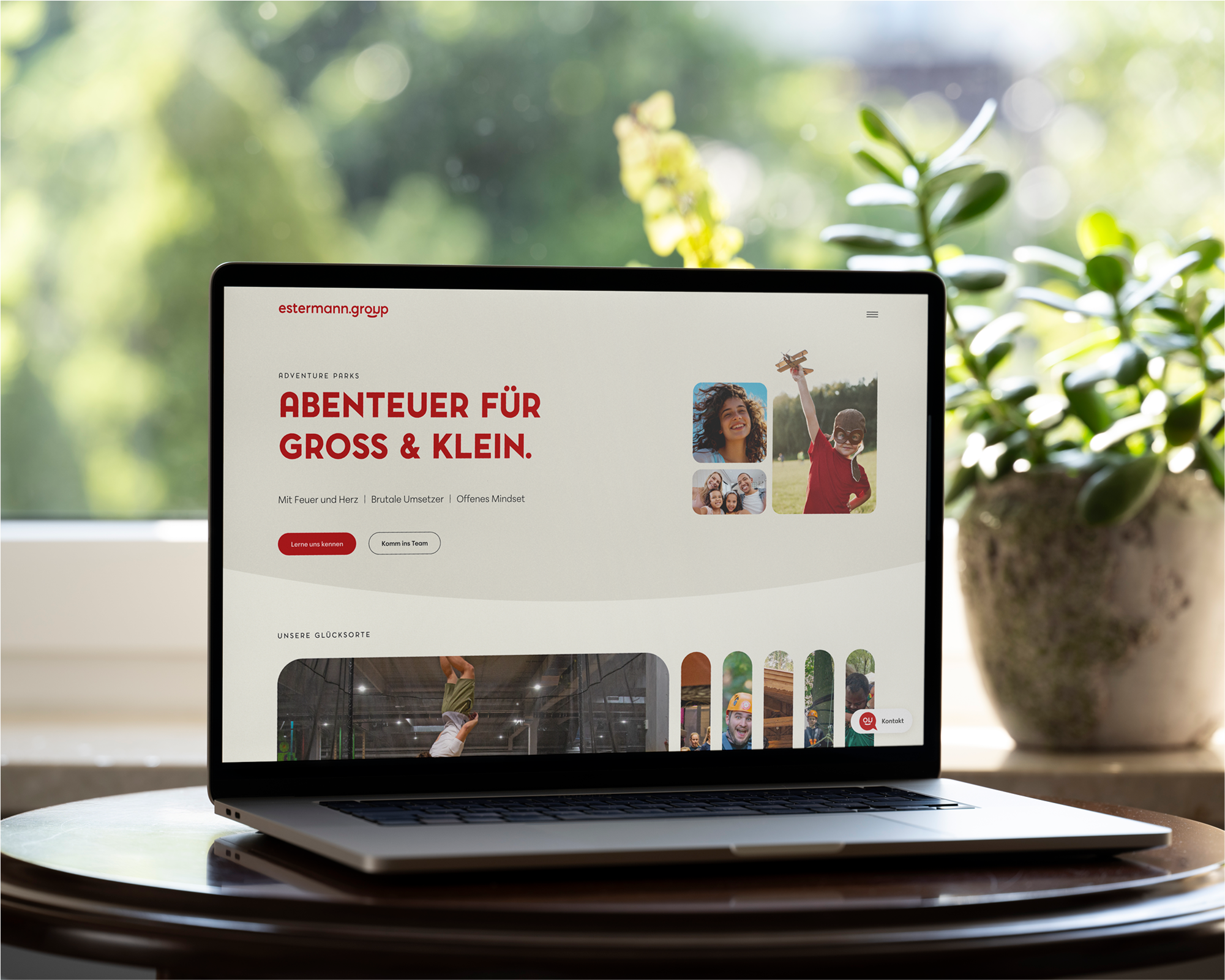 Ein Laptop auf einem Tisch mit Planzen im Hintergrund zeigt die Startseite der Estermann Website