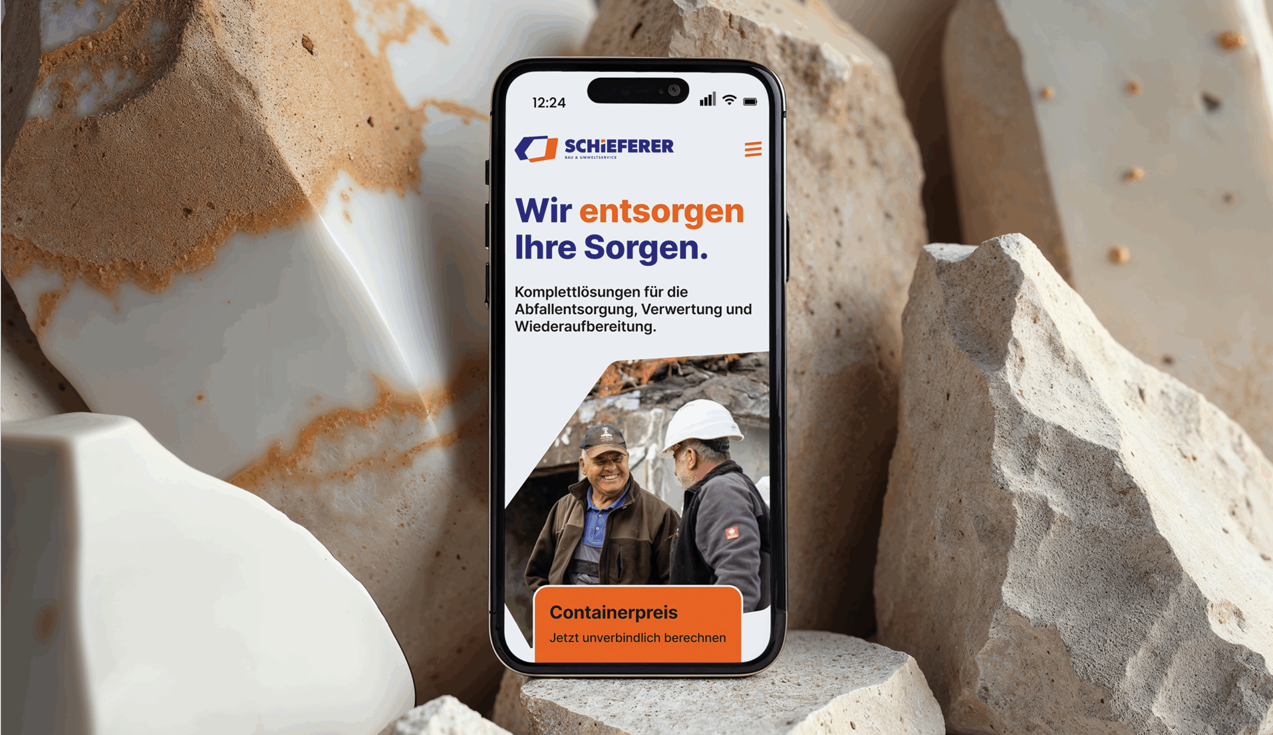 Ein Handy zeigt die Startseite von Schieferer und ist auf großen Steinen platziert
